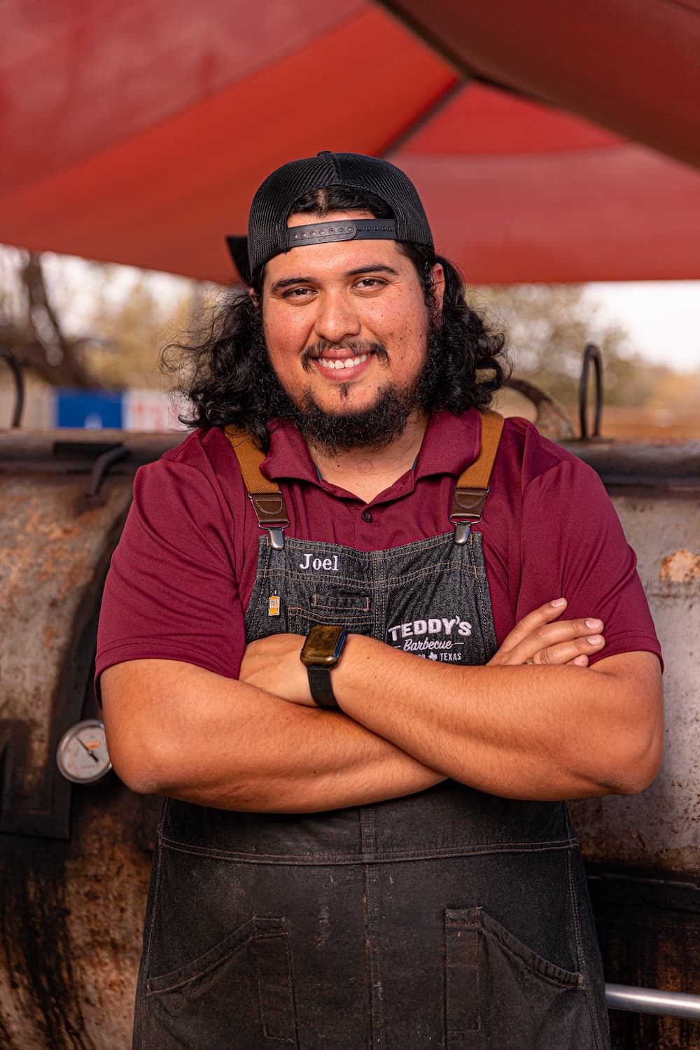 a guy smiling with his arms crossed in front of a smoker
