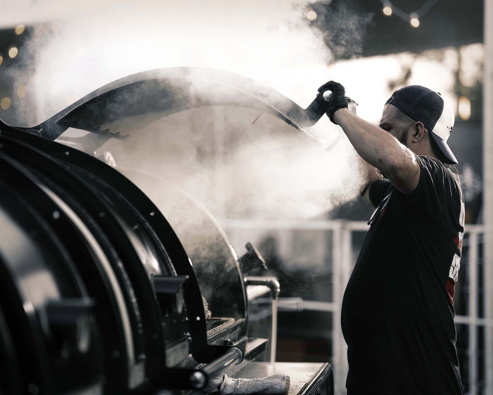 bbq chef opening a smoker letting large amounts of smoke pour out